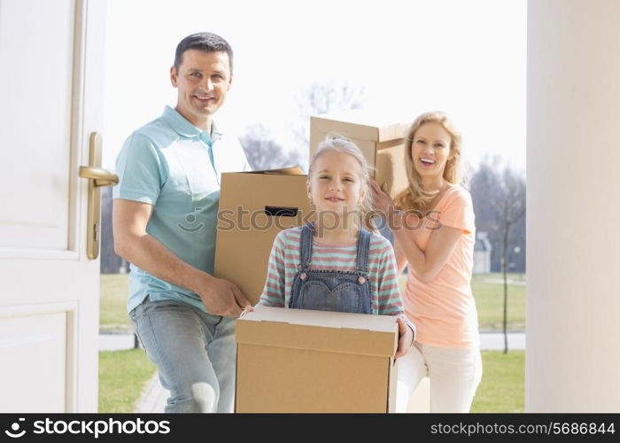 Happy family with cardboard boxes entering new home