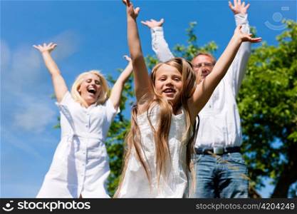 Happy family with child jumping in a meadow in summer