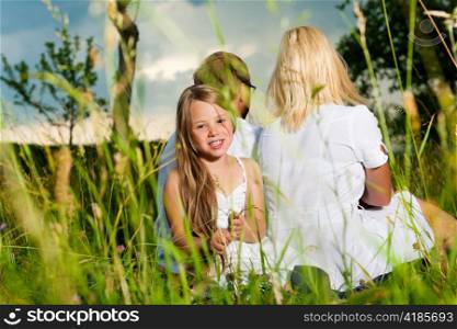 Happy family with daughter girl sitting in a meadow in summer before a storm