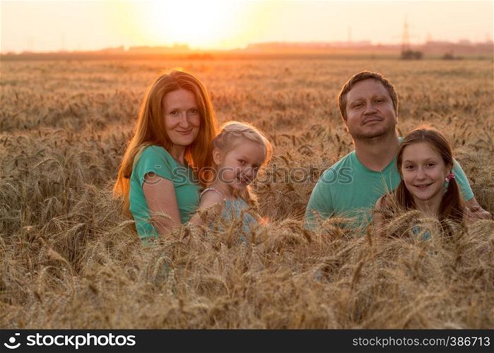 happy family with daughters at the wheat field