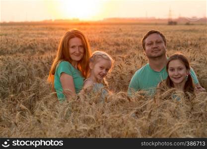happy family with daughters at the wheat field