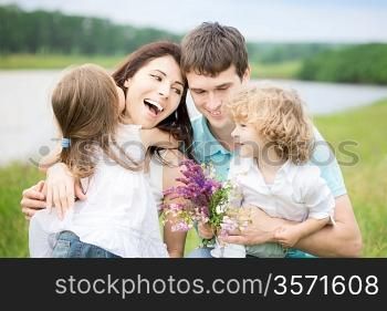 Happy family with flowers having fun outdoors in spring field