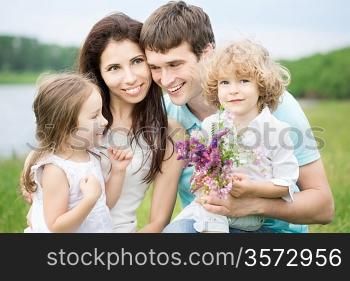Happy family with flowers having fun outdoors in spring field
