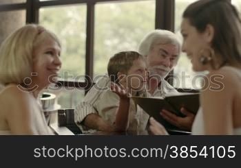 Happy family with husband, wife, child, grandfather and grandmother choosing food and drinks in bar