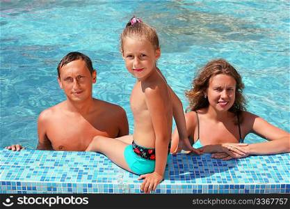 Happy family with little girl bathe in pool, daughter sits near pool