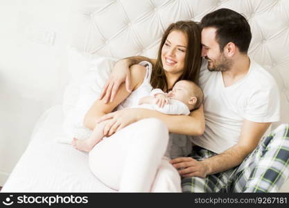 Happy family with newborn baby on the bed in the room