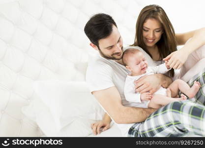 Happy family with newborn baby on the bed in the room