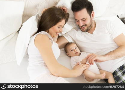 Happy family with newborn baby on the bed in the room