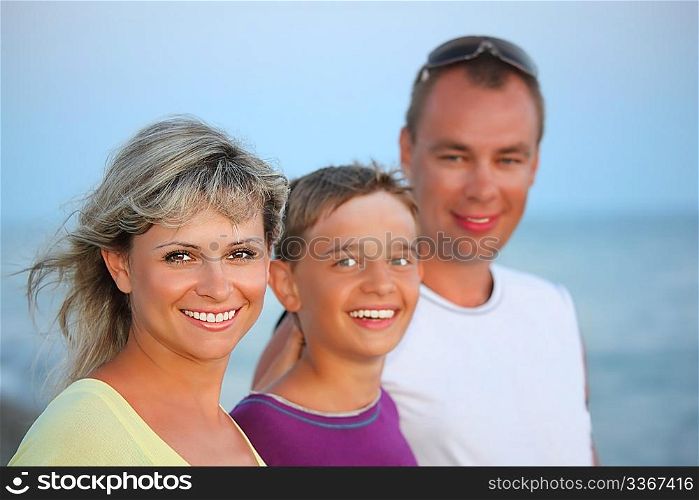 Happy family with smiling boy on beach in evening