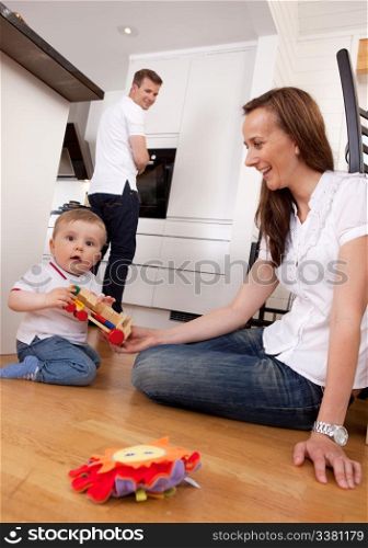 Happy family with son playing on floor with mother and father in the background