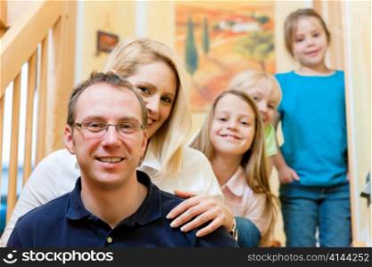 Happy family with three children at home on stair