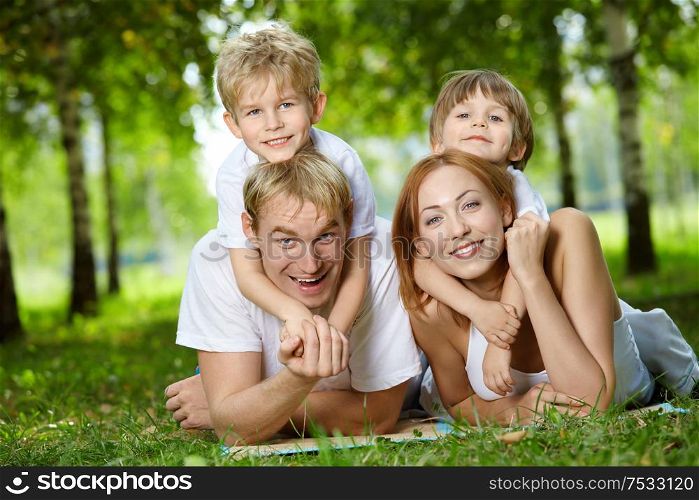 Happy family with two sons frolic on a lawn