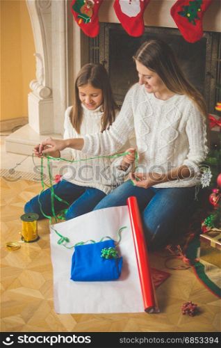 Happy family wrapping Christmas presents at fireplace