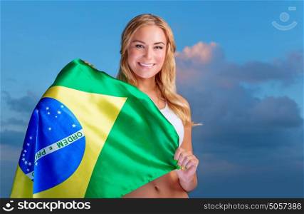 Happy fan of Brazilian football team, cheerful pretty girl on stadium cheering in support, holding up big national flag of Brazil, active people traveling to watch football games