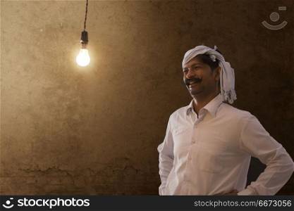 Happy farmer looking at light bulb in his house