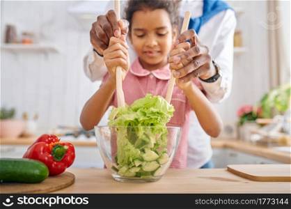 Happy father and daughter cooking salad on breakfast. Smiling family eats on the kitchen in the morning. Dad feeds female child, good relationship. Father and daughter cooking salad on breakfast