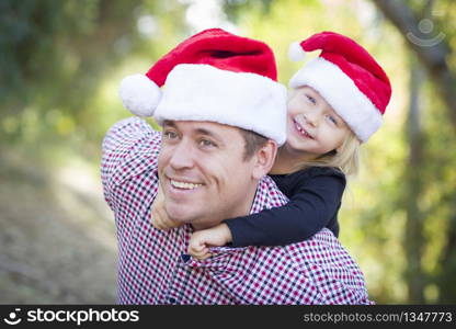 Happy Father and Daughter Having Fun Wearing Santa Hats Outdoors.