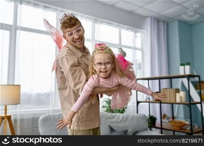 Happy father and excited little daughter wearing fairies costume having fun at home. Father and daughter wearing fairies costume having fun
