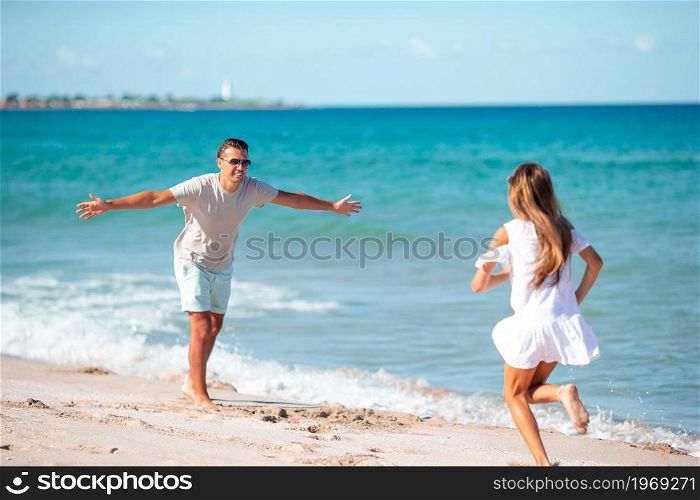 Happy father and his adorable daughter at white sandy beach having fun. Little girl and happy dad having fun during beach vacation