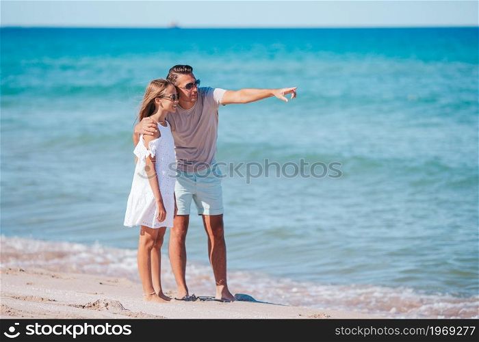 Happy father and his adorable daughter at white sandy beach having fun. Little girl and happy dad having fun during beach vacation