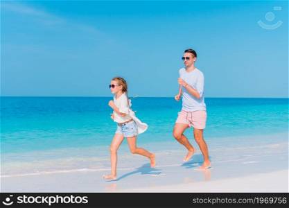Happy father and his adorable little daughter at white sandy beach having fun. Little girl and happy dad having fun during beach vacation