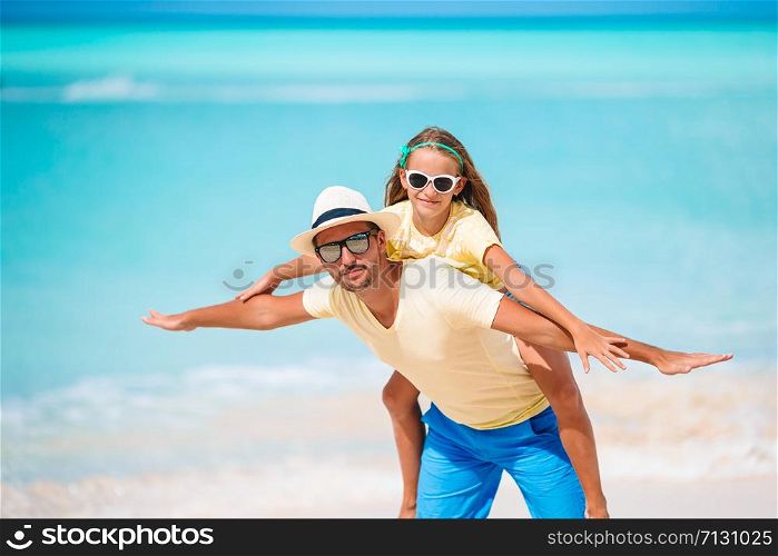 Happy father and his adorable little daughter at white sandy beach having fun. Little girl and happy dad having fun during beach vacation