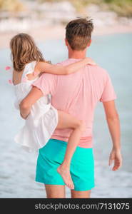 Happy father and his adorable little daughter at white sandy beach walk and talk. Little girl and happy dad having fun during beach vacation