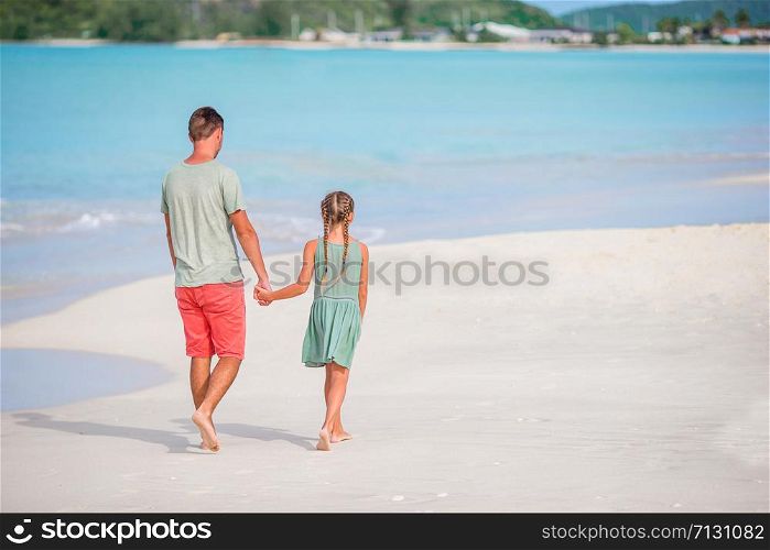 Happy father and his adorable little daughter at white sandy beach walk and talk. Little girl and happy dad having fun during beach vacation