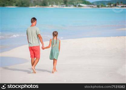 Happy father and his adorable little daughter at white sandy beach walk and talk. Little girl and happy dad having fun during beach vacation