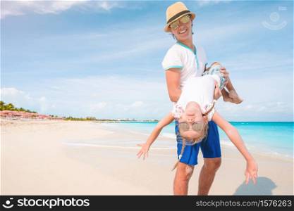 Happy father and his adorable little girl on the beach having fun together. Little girl and happy dad having fun during beach vacation