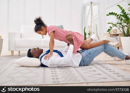 Happy father and little daughter play in living room.Dad and female child leisures in their house together, good relationship. Happy father and daughter play in living room