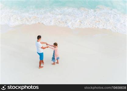 Happy father and little girl on white sandy beach have fun together. Little girl and happy dad having fun during beach vacation