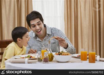 Happy father and son having pizza at restaurant