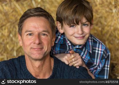 Happy father and son man and boy smiling sitting on hay or straw bales