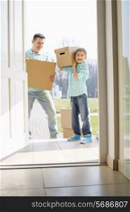 Happy father and son with cardboard boxes entering into new house