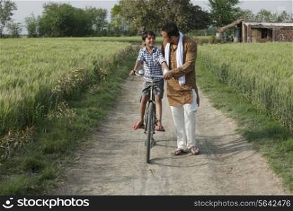 Happy father assisting son to ride cycle
