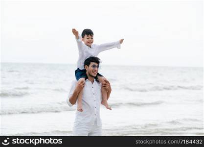 Happy father carrying his son on the neck on a tropical sand beach in summer.. Happy father carrying his son on the neck.