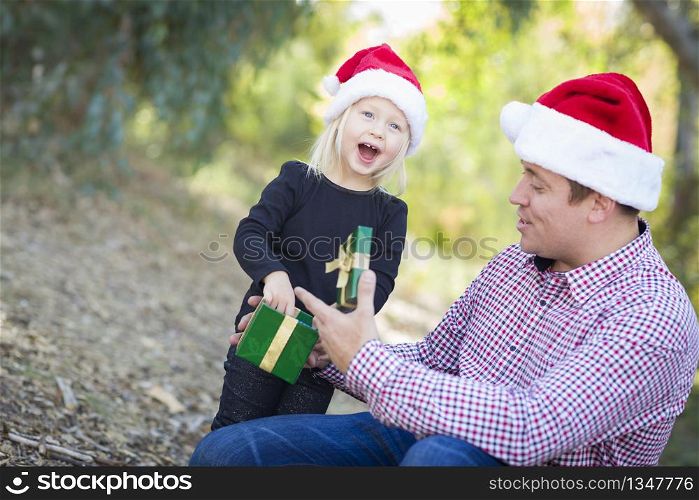 Happy Father Giving Young Daughter A Christmas Gift Outdoors.