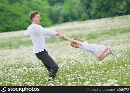 Happy father play with daughter in big camomile mountain meadow. Emotional, love and care scene.
