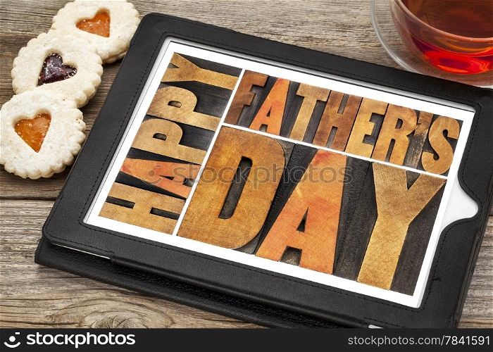 happy father&rsquo;s day - a word abstract in antique wood letterpress printing blocks on a digital tablet with heart biscuit cookies