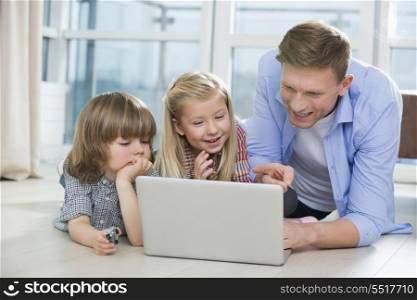 Happy father showing something to children on laptop at home