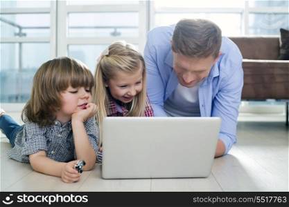 Happy father with children using laptop on floor in living room