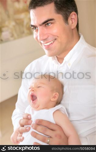 Happy father with yawning daughter on hands at home, enjoying bedtime, cheerful parenthood, love and happiness concept