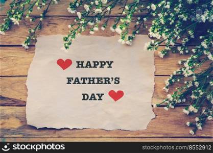 Happy Fathers day on brown paper with white flower on wooden board