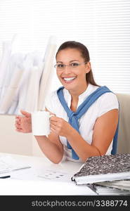 Happy female architect with coffee sitting at the office