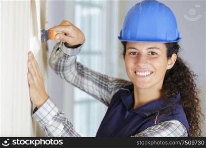 happy female builder plastering a wall