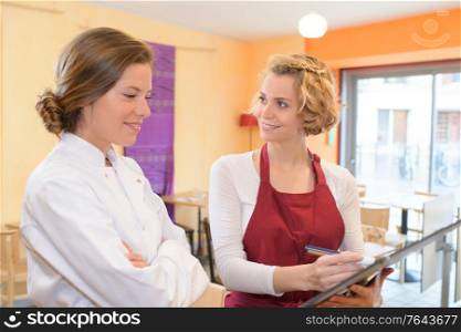 happy female chef and waitress discussing tonights menu