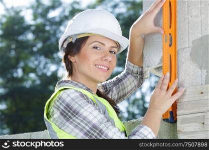 happy female constructor working with a level on a wall