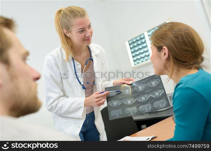 happy female doctor reading xray results to couple