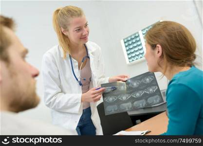 happy female doctor reading xray results to couple